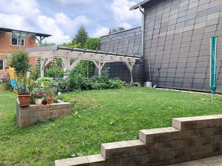 Blick in den Garten mit Freisitz und Neubau Wohnhaus im Hintergrund - Zweifamilienhaus in 99331 Geratal mit 235m² kaufen